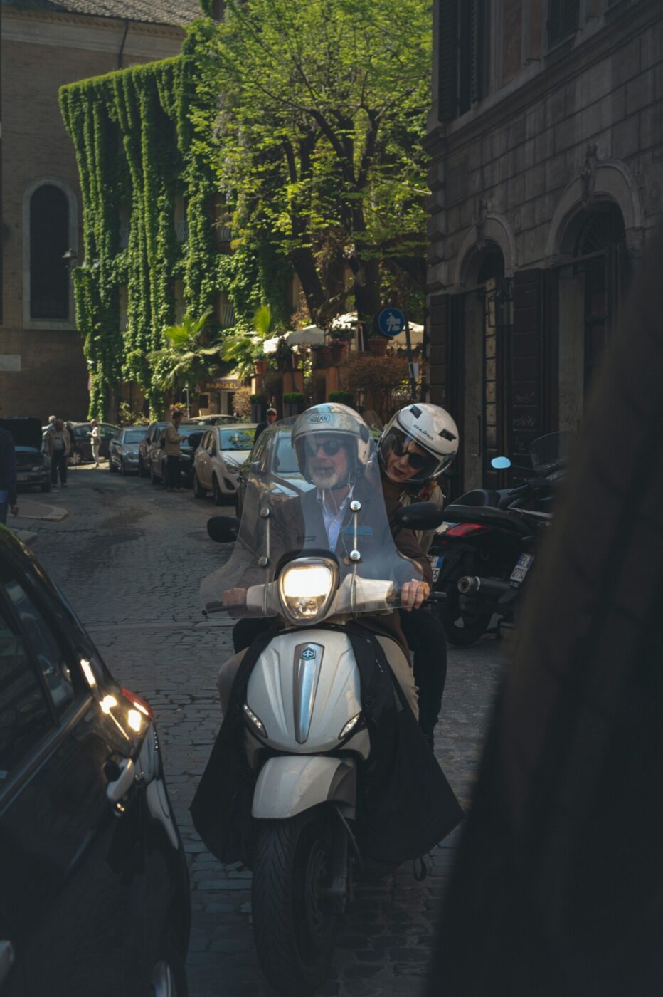 a couple squeezing through cars on a vespa
