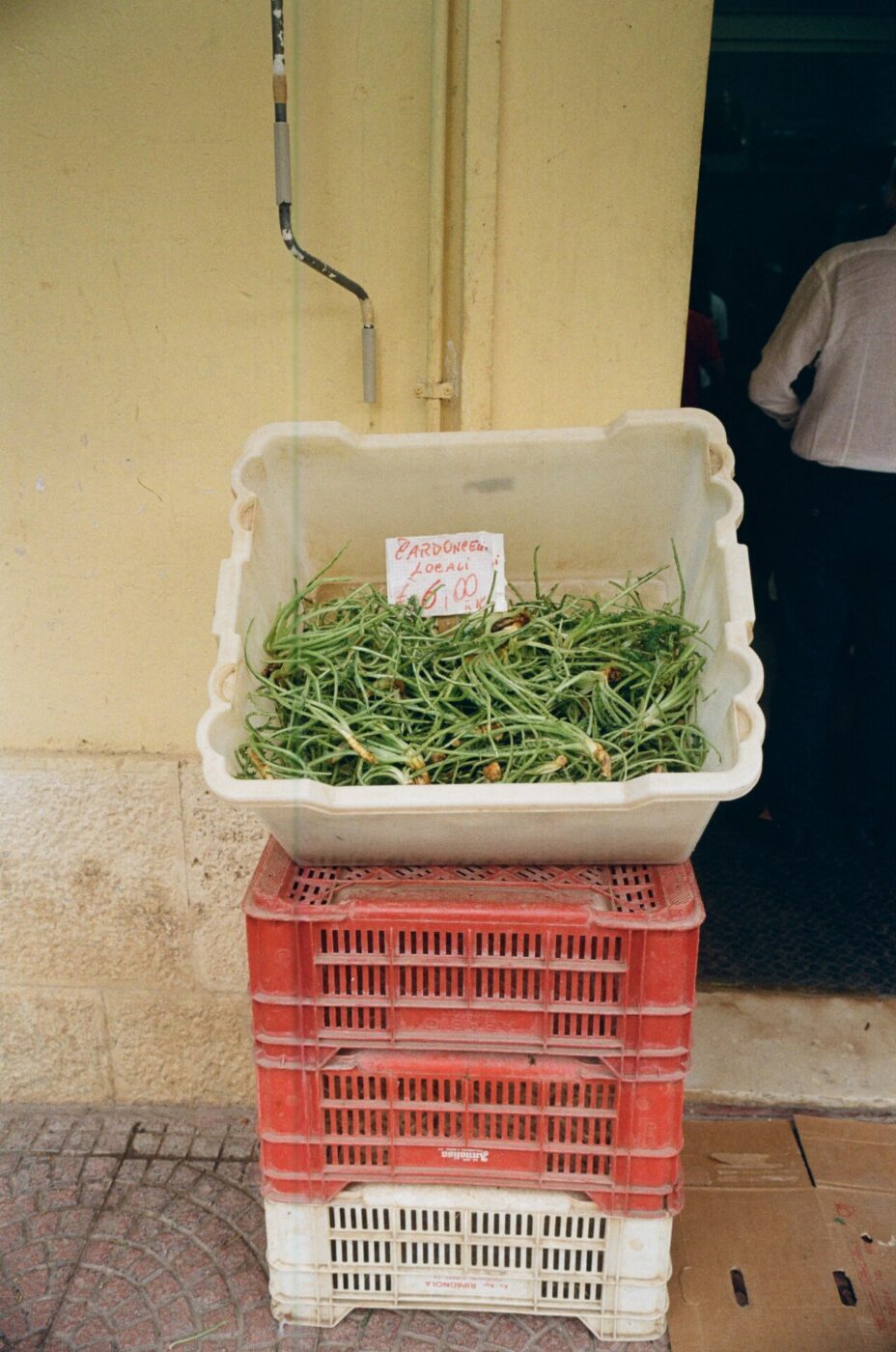 a container of greens for sale outside a shop in Altamura