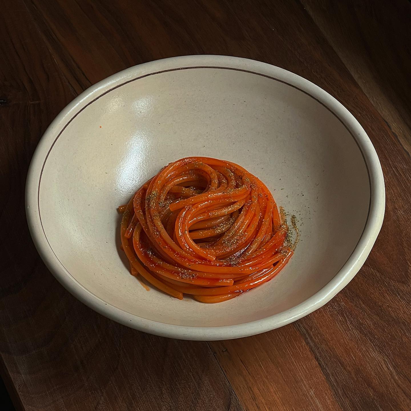 A white bowl with pasta and red sauce perfectly arranged in the center from Ahimè in Bologna