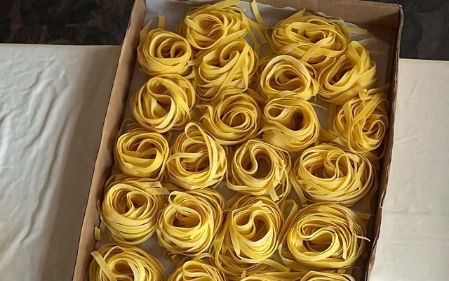 A tray of fresh tagliatelle arranged in nests