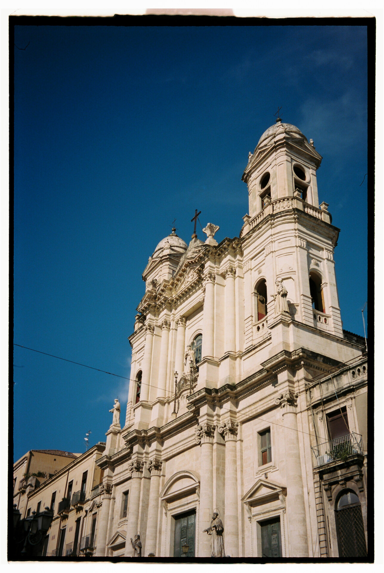 Photography by Gina Spinelli of the facade of a tall white church in Catania