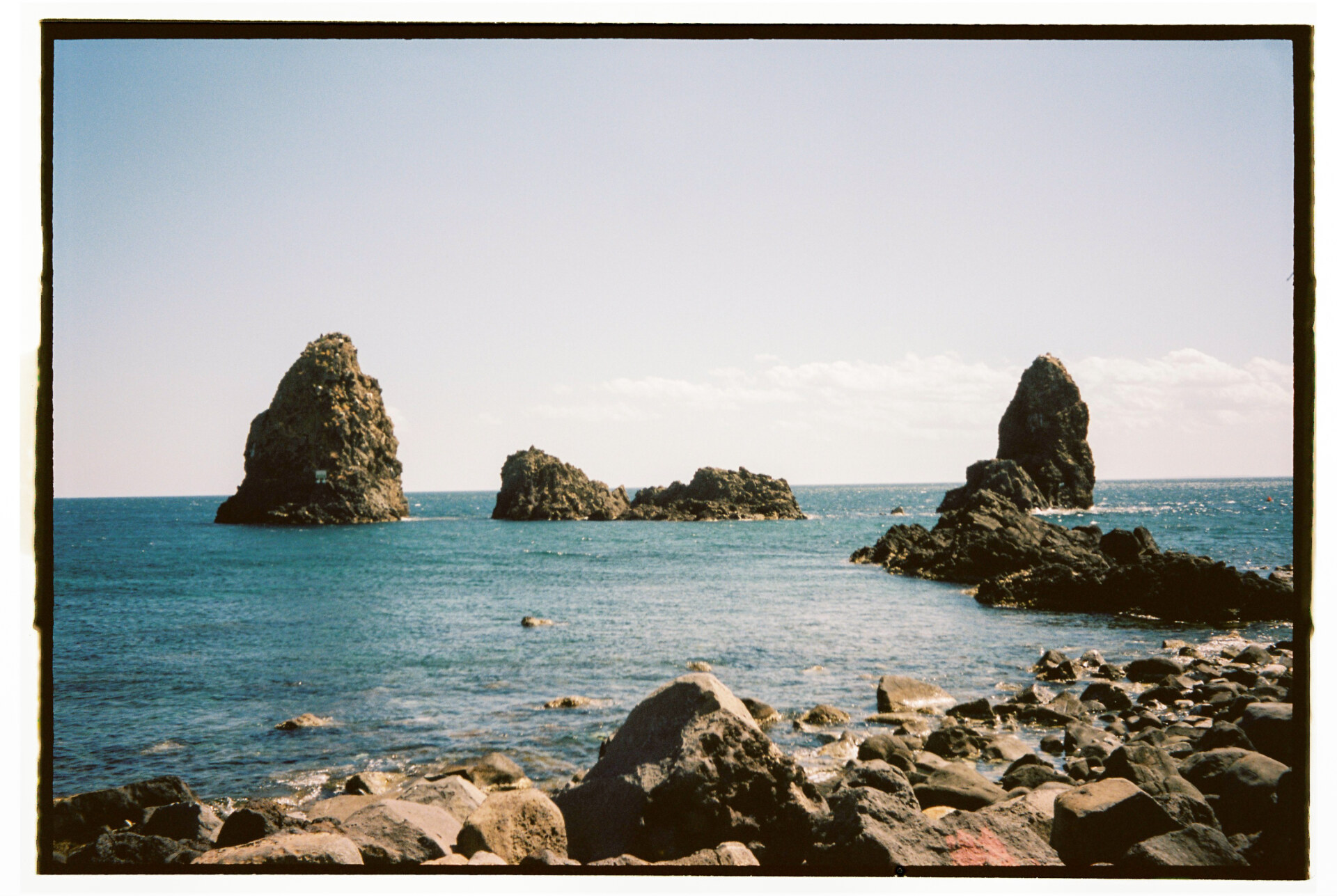 Photography by Gina Spinelli of three large rocks off of the coast of Catania off Aci Trezza,