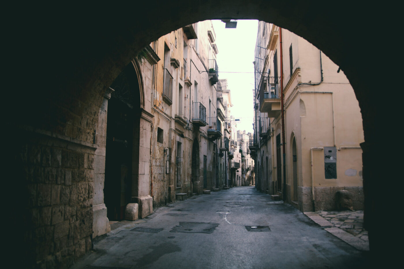 a vintage photo taken through an archway of a street in Altamura