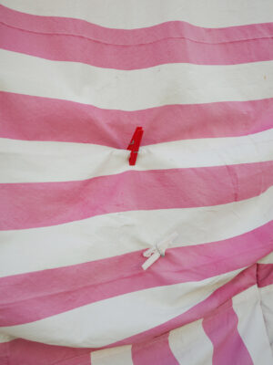 photo by Leandro Colantoni: a pink and white striped blanket with two red and white clothespins