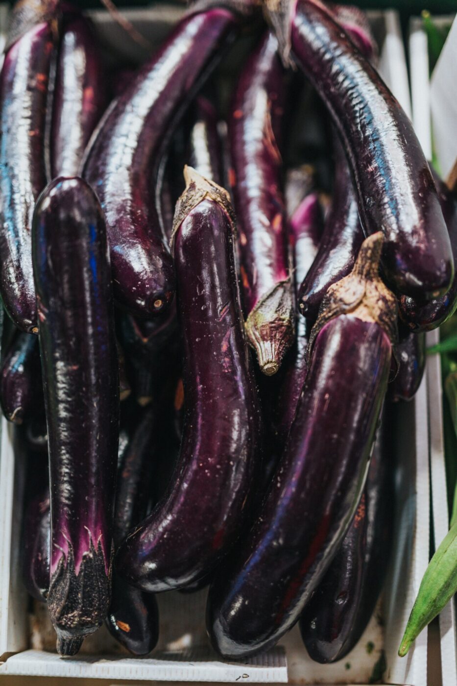 a pile of long, thin, deep purple eggplants