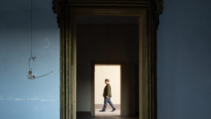chef Ciccio Sultano walking towards the left of the photo in the distance, photographed through the door frame