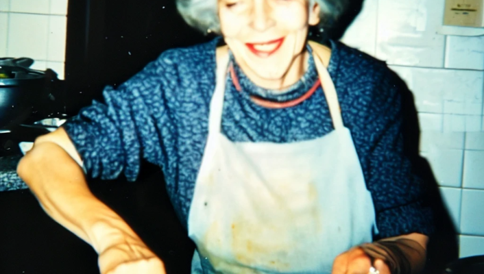 photo by Roberto Beragnoli: an Italian grandma wearing a white apron in a white tile kitchen making homemade pasta