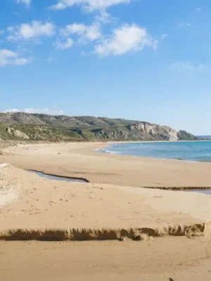 the tan, sandy, curving beach of torre salsa with a clear blue sky