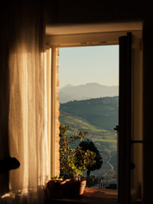 a view out the sunny window of a curving road through picturesque hills in Italy