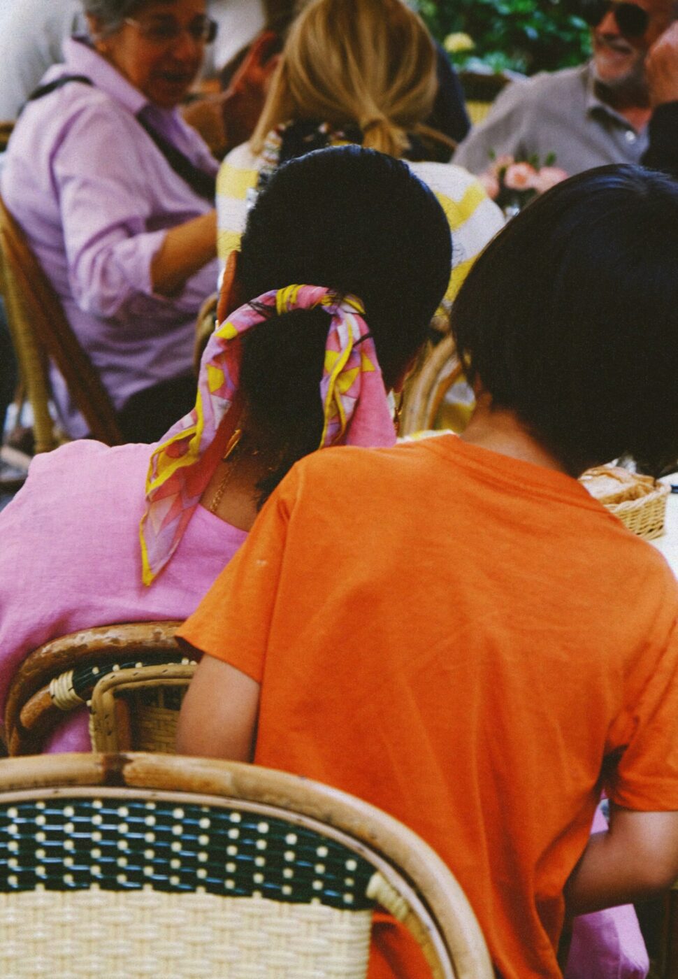 a woman and a young boy shown from the back in a crowded restaurant in Florence, the woman has a scarf in her hair and the man had an orange shirt