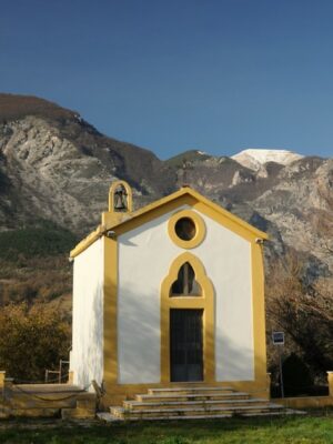 Civitella in Maiella - a small white church with yellow trim standing alone at the foot of mountains