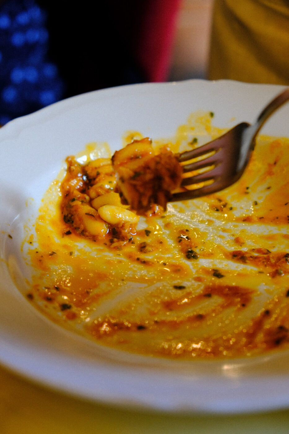 a nearly empty plate of pasta with red sauce at Cibreo with a fork holding a bite and the trails of sauce left on the plate