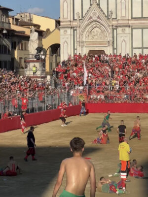 a photo of the calcio storico in Piazza Santa Croce and crowds of onlookers dressed in red