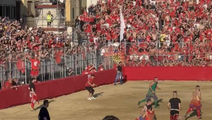 a photo of the calcio storico in Piazza Santa Croce and crowds of onlookers dressed in red