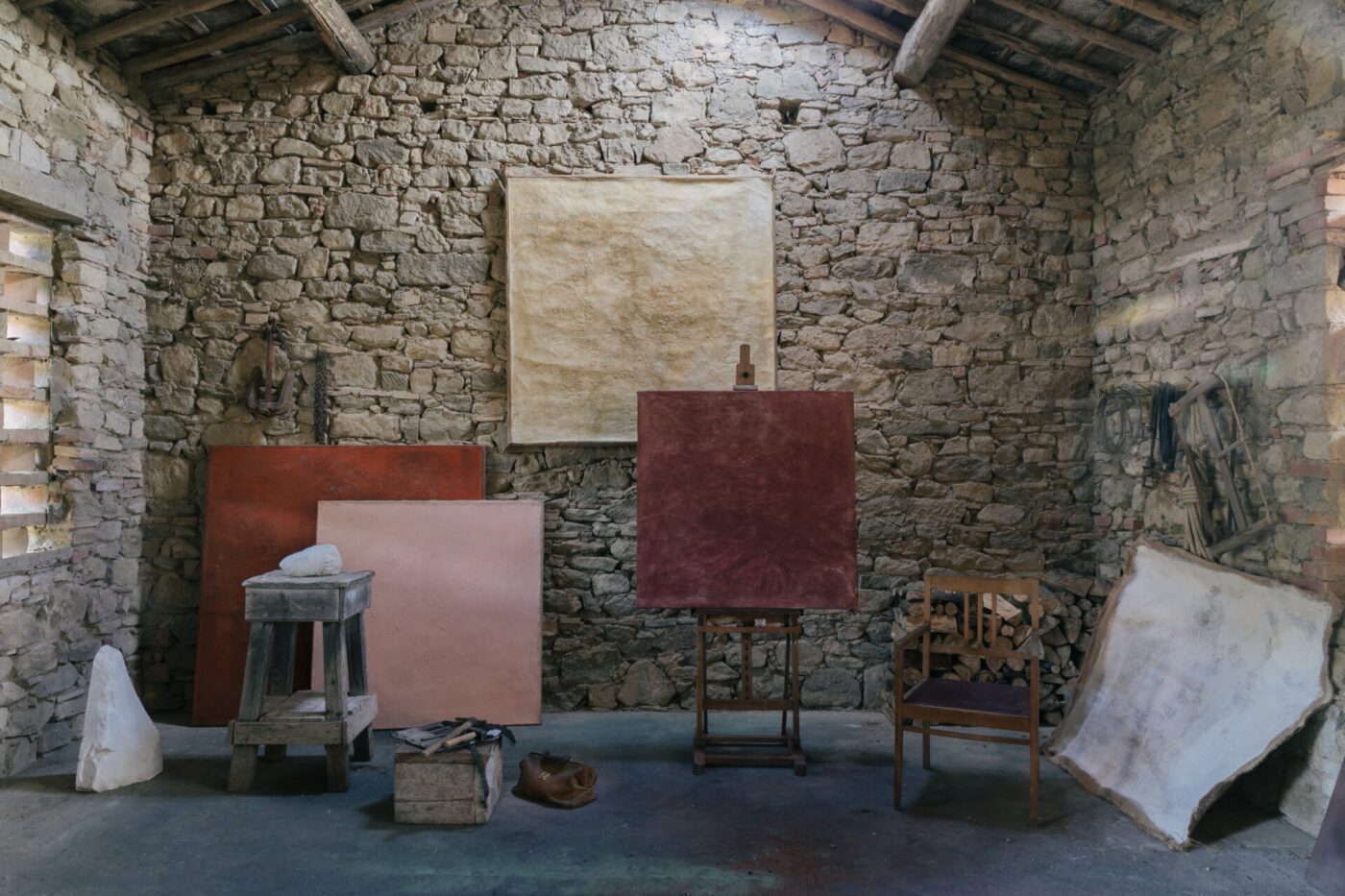 the inside of a stone house with various art pieces including three large canvases in various shades of pink