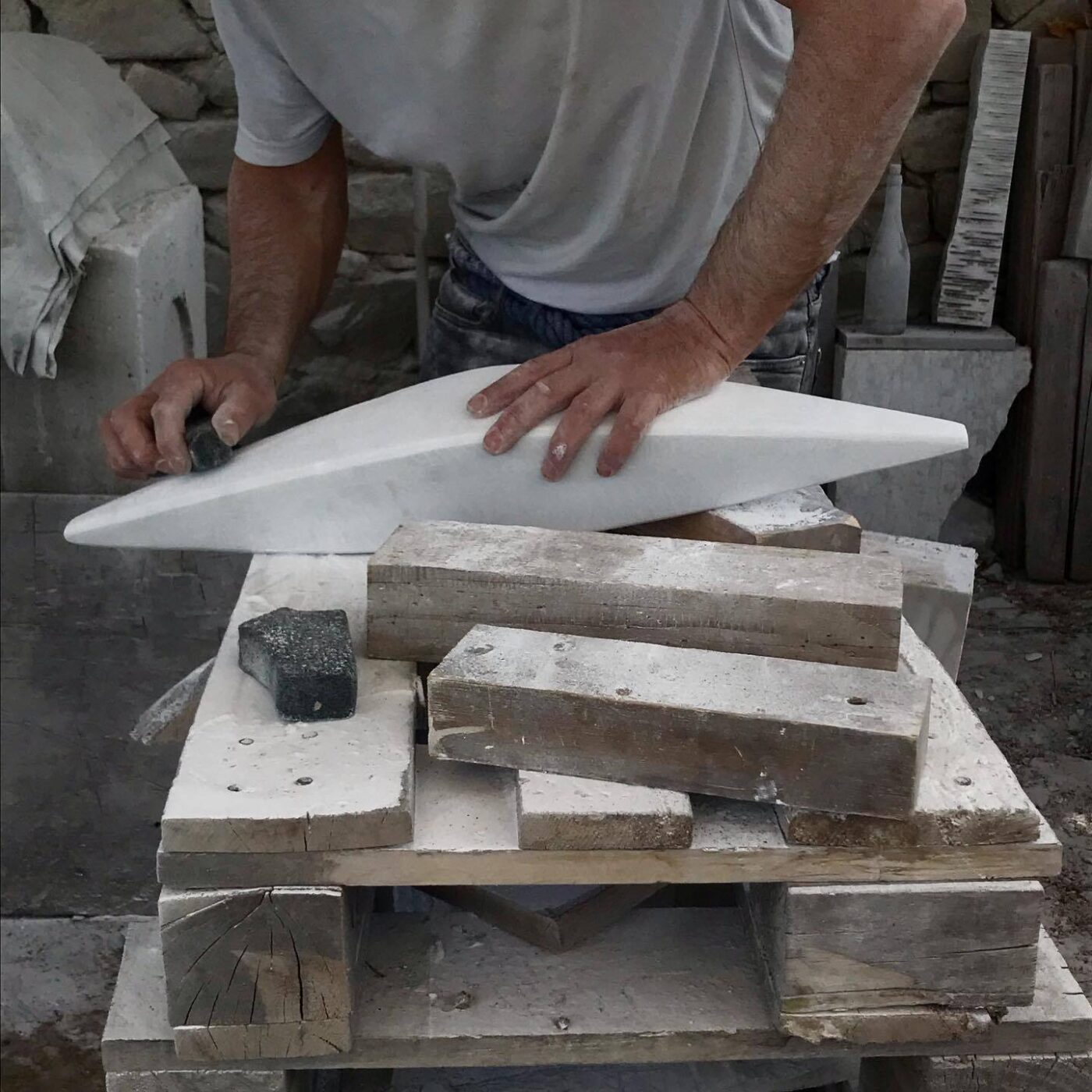 a close up of sculptor Lorenzo Brinati sculpting a piece of white marble resting on a table