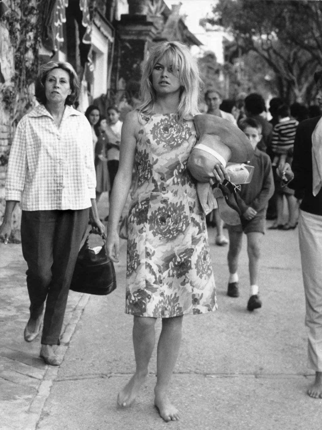 a vintage, black and white photo of Cristina Nannini and Brigitte Bardot walking barefoot through Capri
