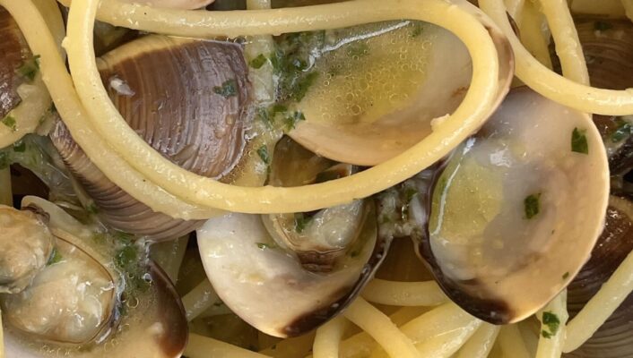 a close up image of Spaghetti alle Vongole showing clams in their shell and spaghetti wrapped around it