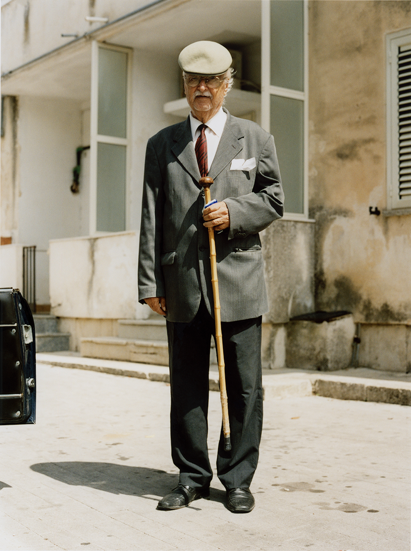 photo by Carlo Piro – an old man dressed in a suite holding a cane