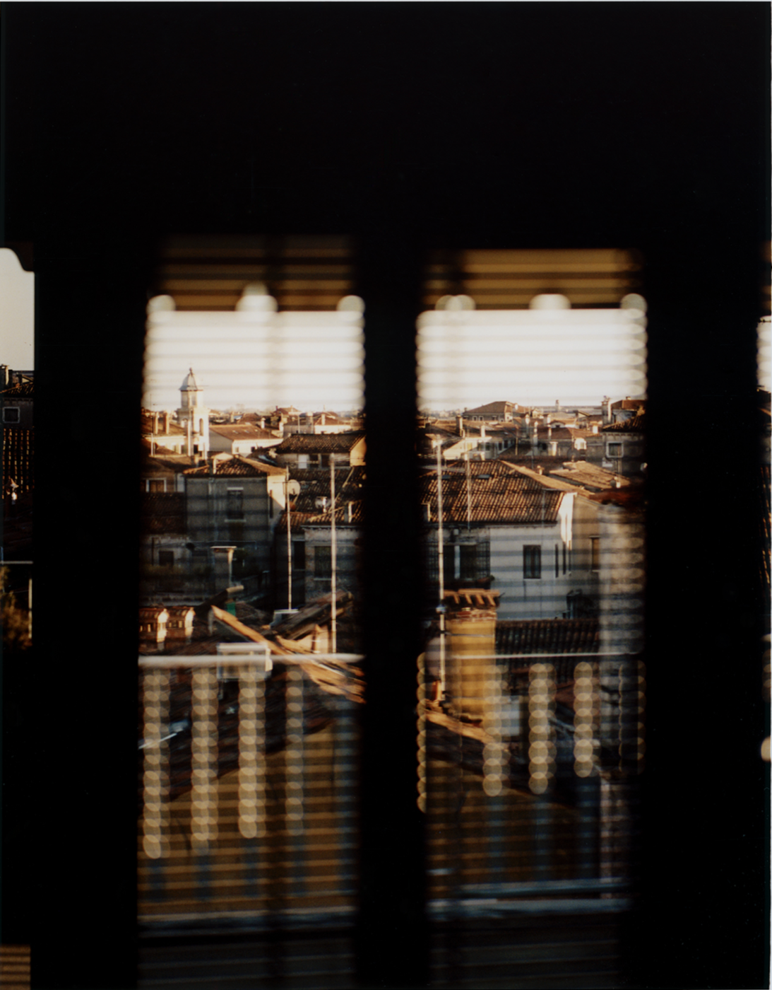 a photo of carlo piro of the view through the persiana (blinds) of a city window