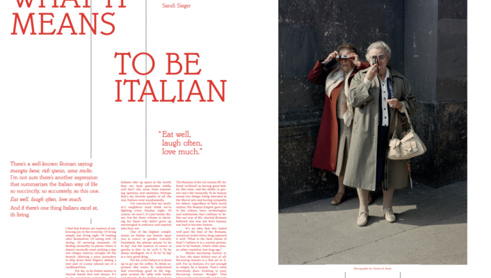 What It Means To Be Italian - Two older women in trench coats and sunglasses pose playfully on a city sidewalk; text on the left.