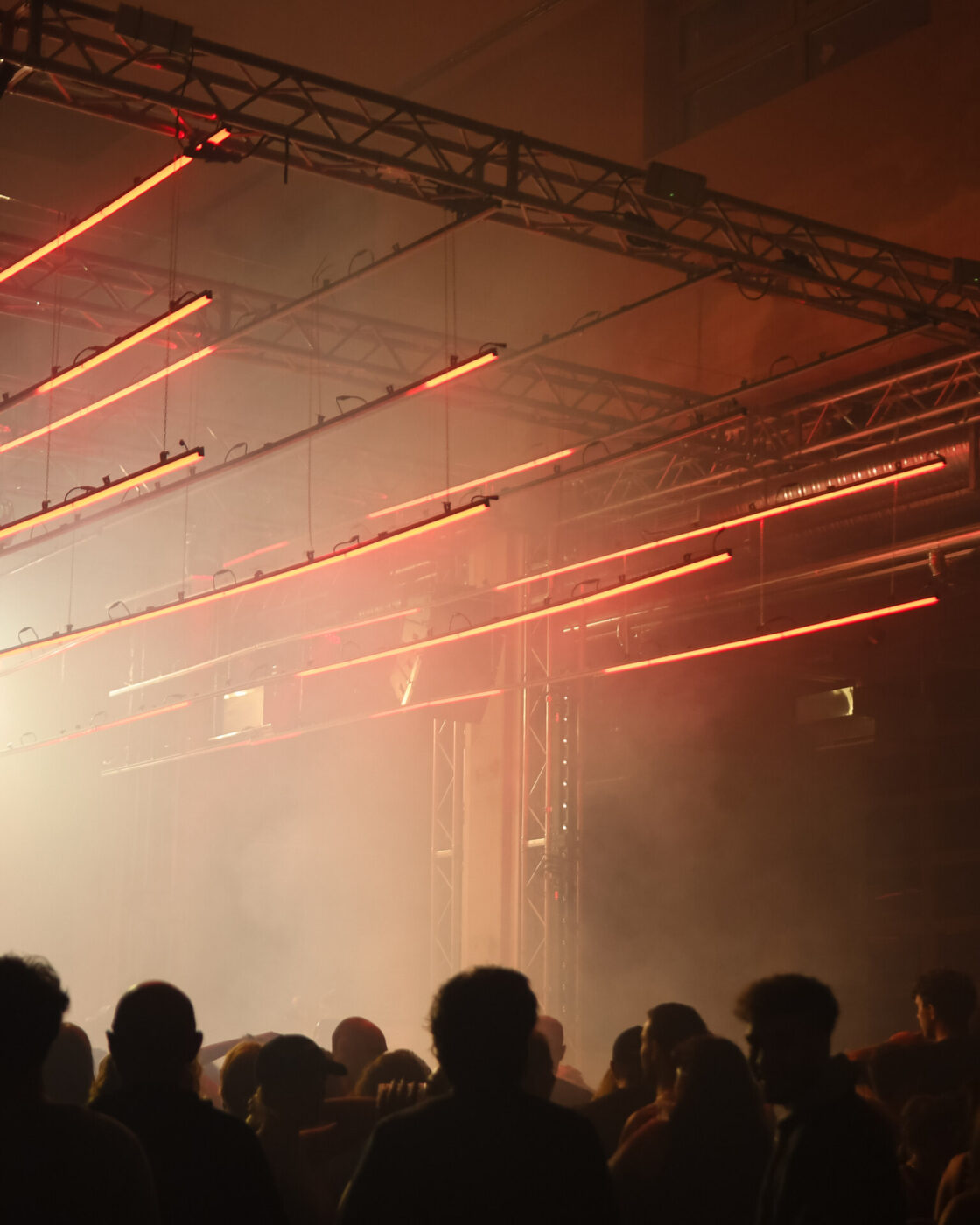 the inside of Lattexplus - a crowded club with fog and orange lazer lights and the dark silhouettes of people