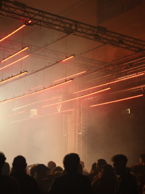 the inside of Lattexplus - a crowded club with fog and orange lazer lights and the dark silhouettes of people