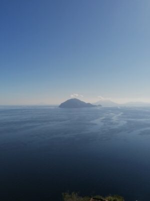 the island of alicudi taken from far away poking up out of the blue sea