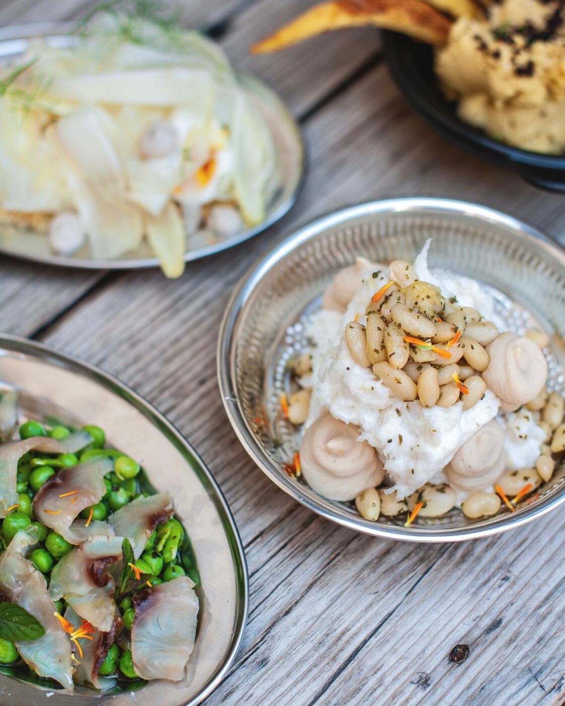 four dishes from the restaurant Venissa on a wooden table