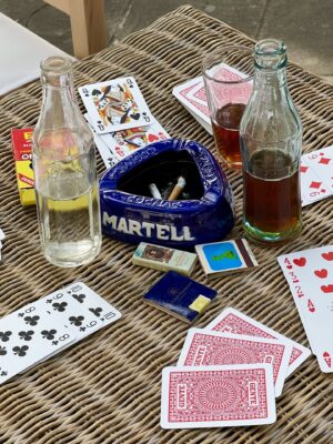 a table with a card game, ash trays, and half finished drinks
