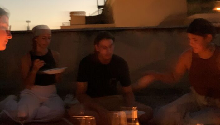 a candlelit picnic ona rooftop at sunset with four friends sitting around