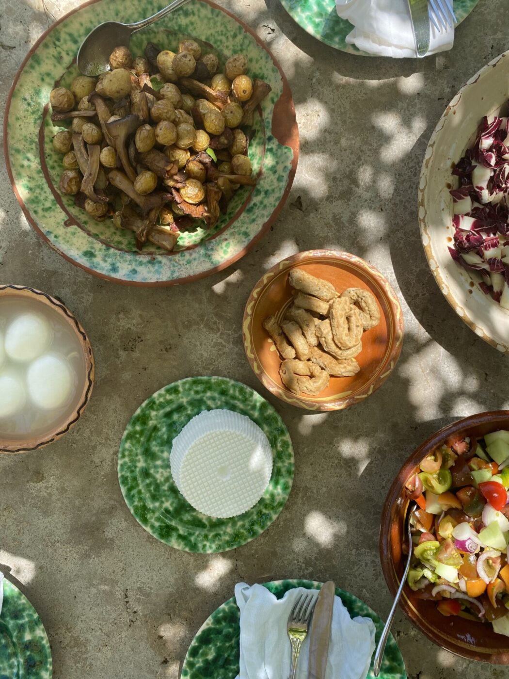 a table filled with Pugliese food like taralli and cheese in beautiful ceramic dishes