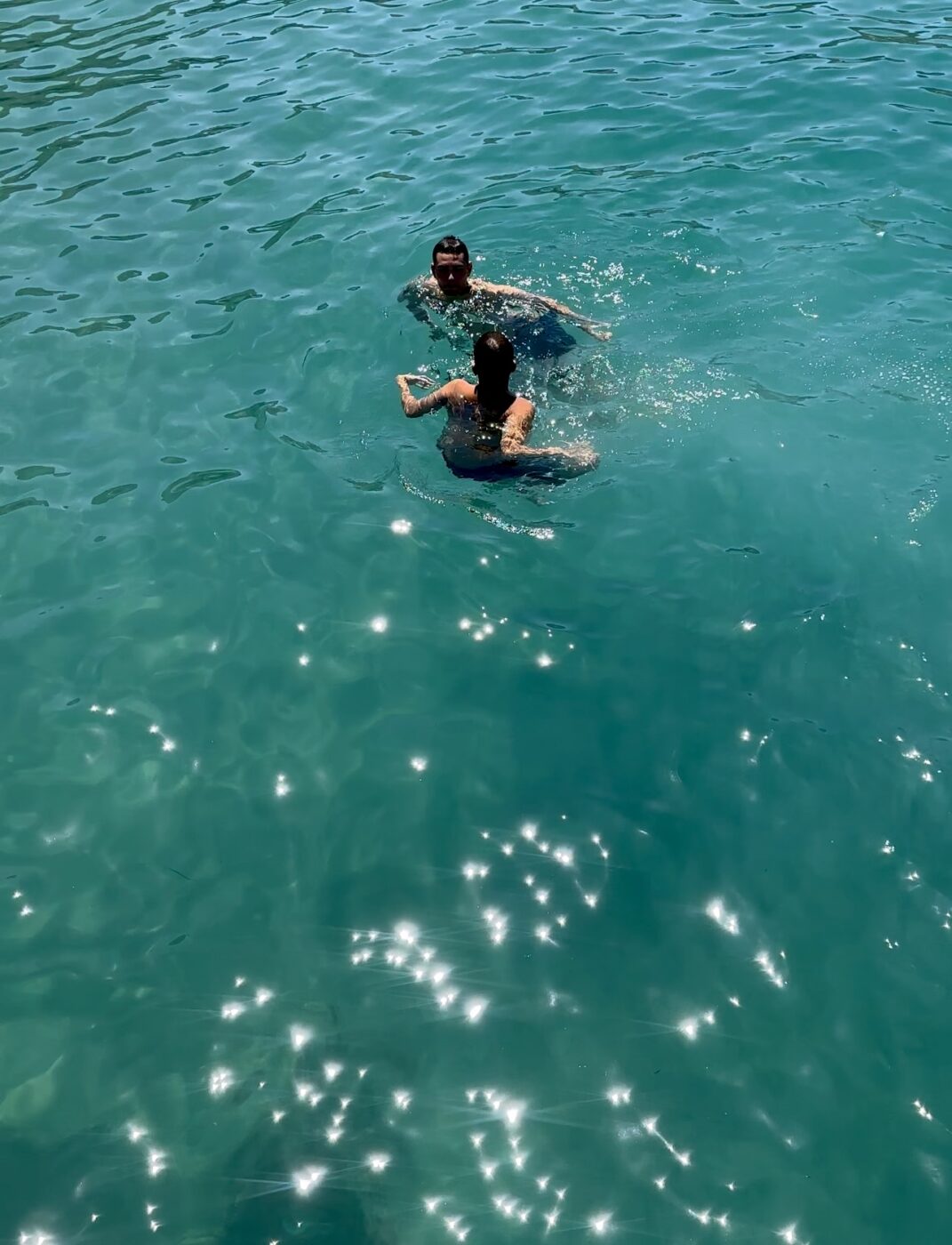two people floating in crystal clear blue water