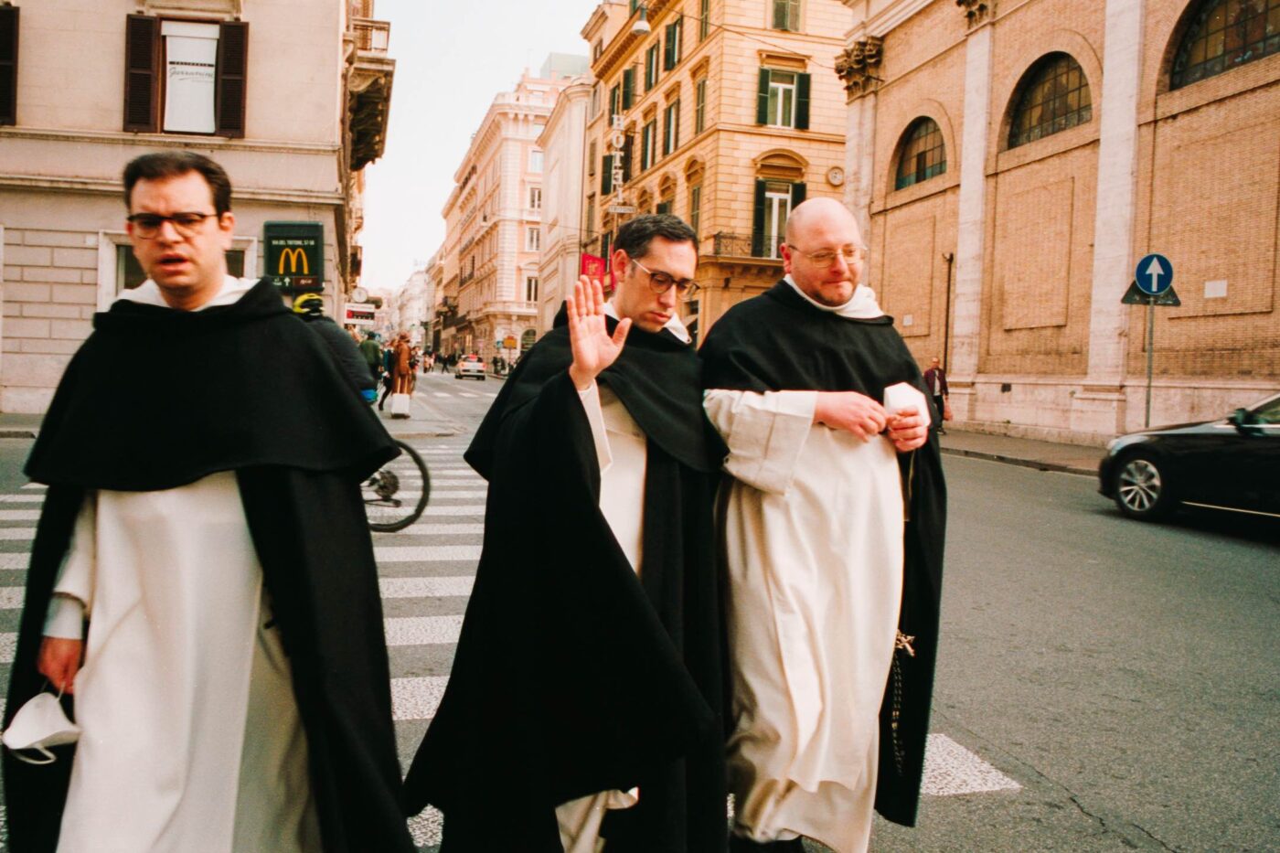 Photography by Lorenzo Gargiulo of three priests walking down the street in Rome in front of a McDonald's