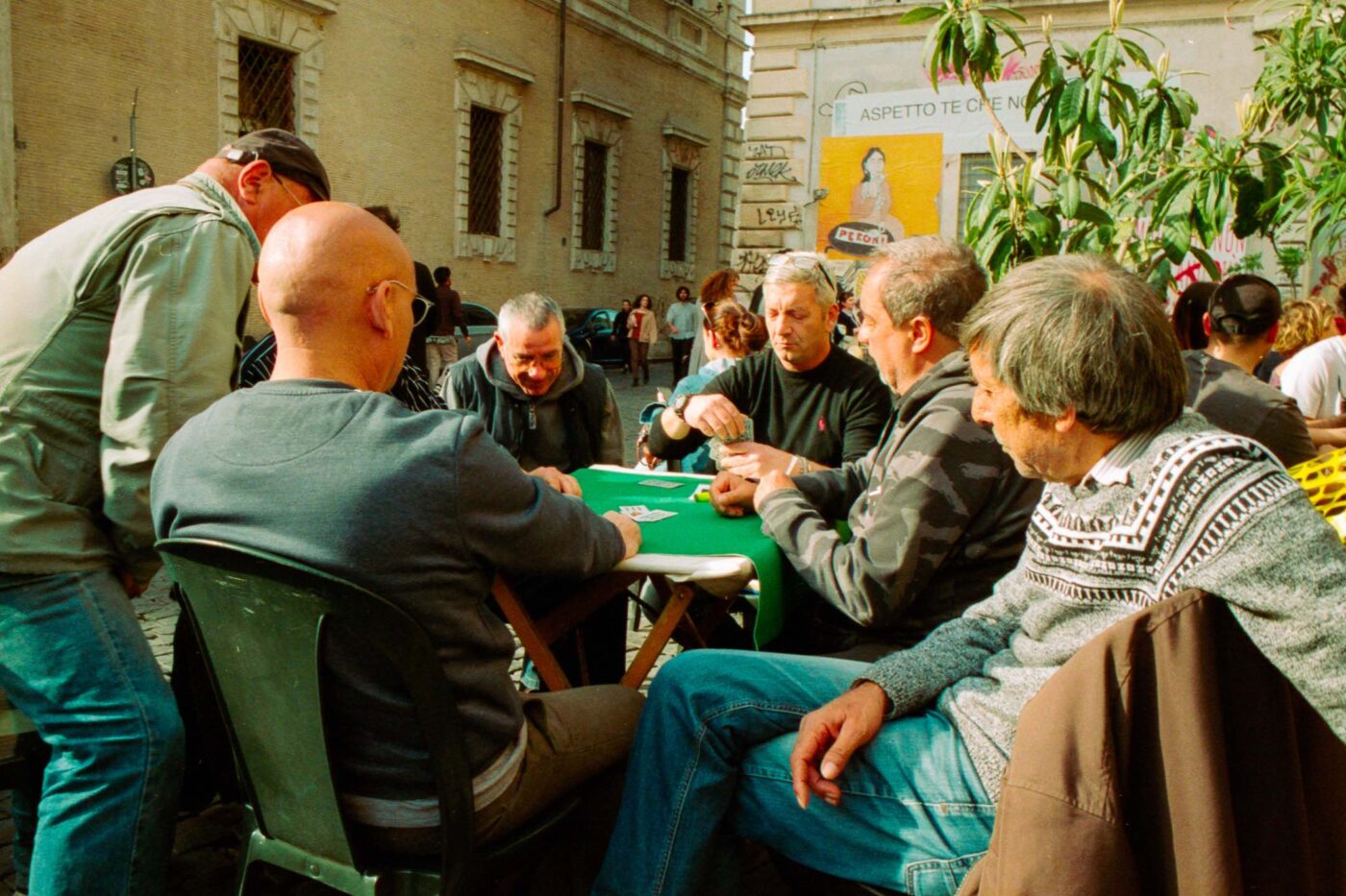 Photography by Lorenzo Gargiulo of men sitting around a table in a piazza in Rome playing cards