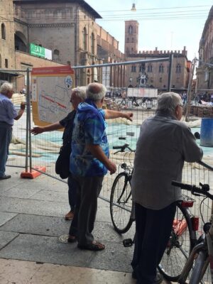 four Umarells in Bologna shown standing and pointing at a construction sight