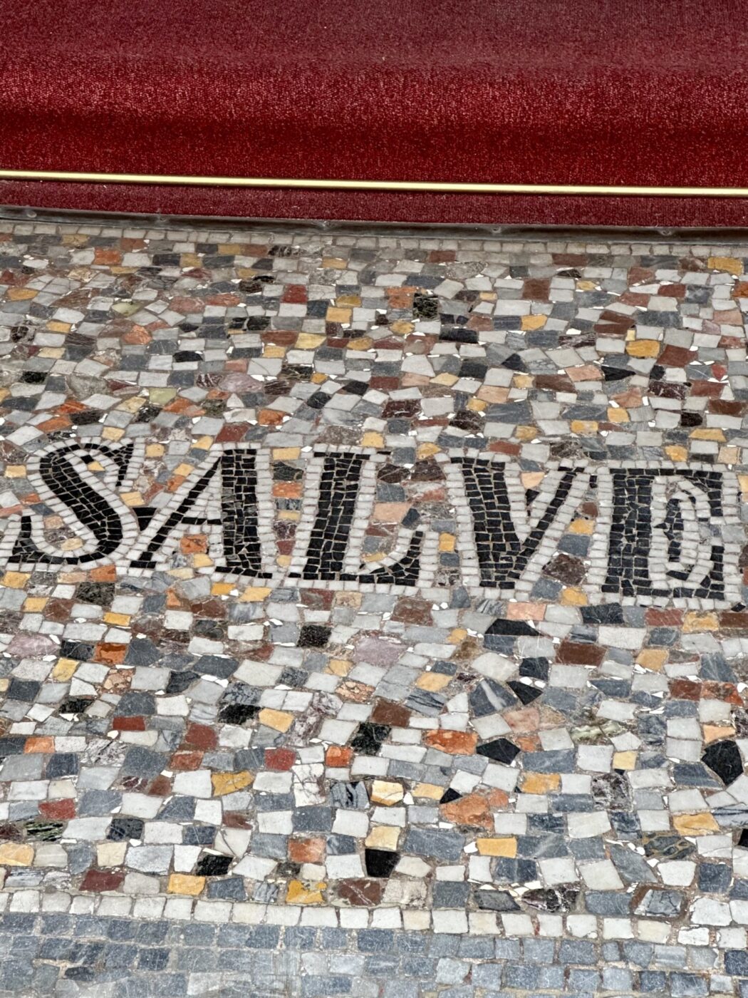 a tile sign on the ground that says "salve"