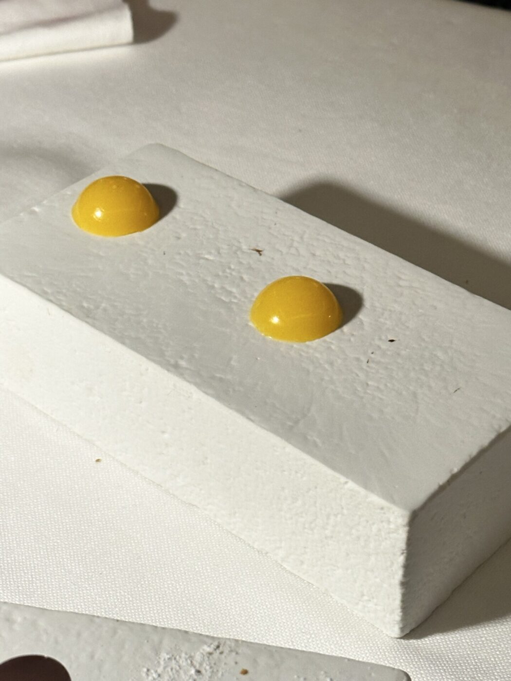 a white square with two yellow droplets on top at a fancy restaurant in Italy