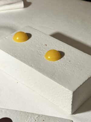 a white square with two yellow droplets on top at a fancy restaurant in Italy