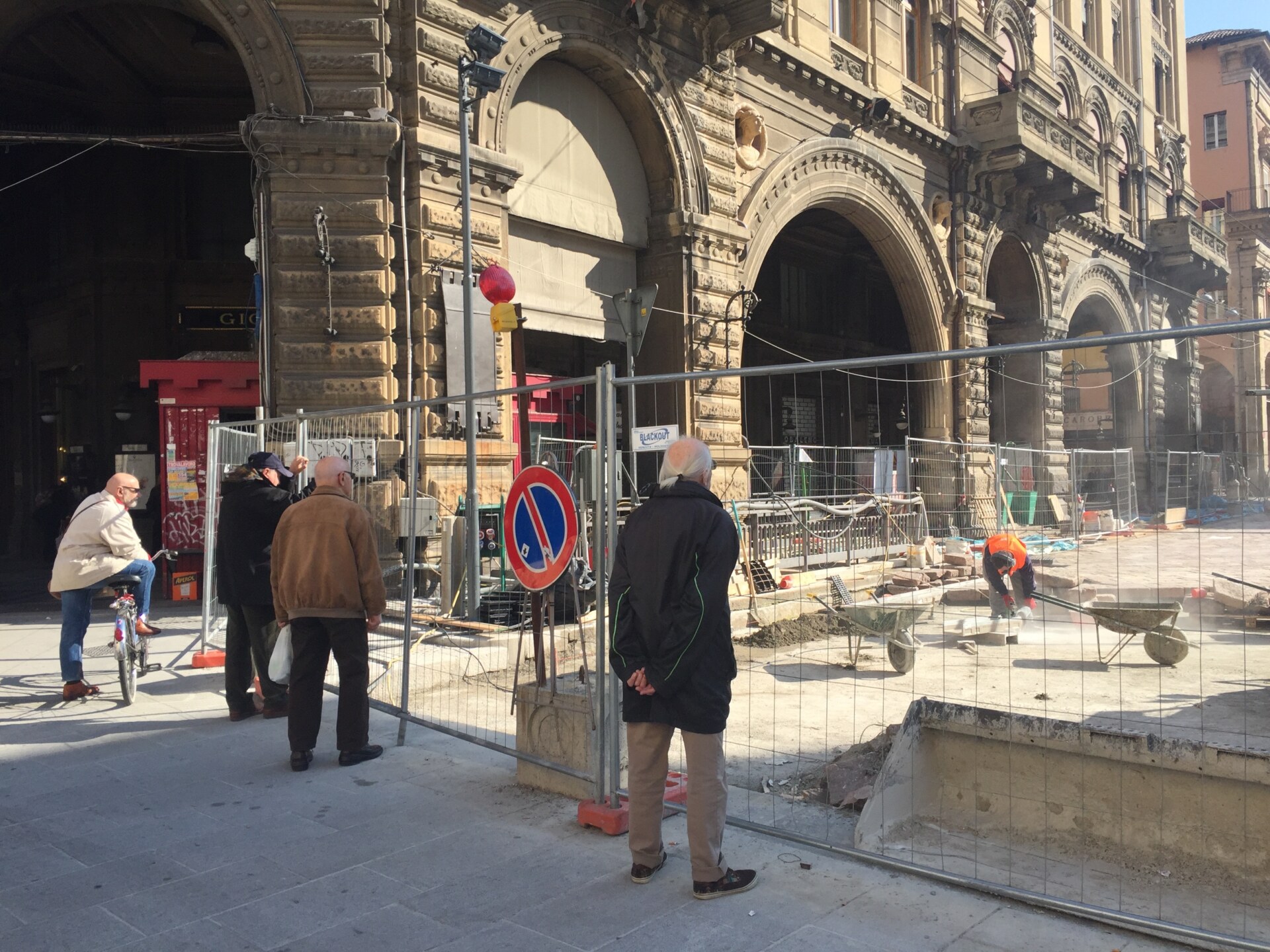 three Umarells in Bologna against the porticos standing and looking at a construction sight