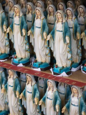 rows of identical figurines of Mary dressed in a light blue robe for sale