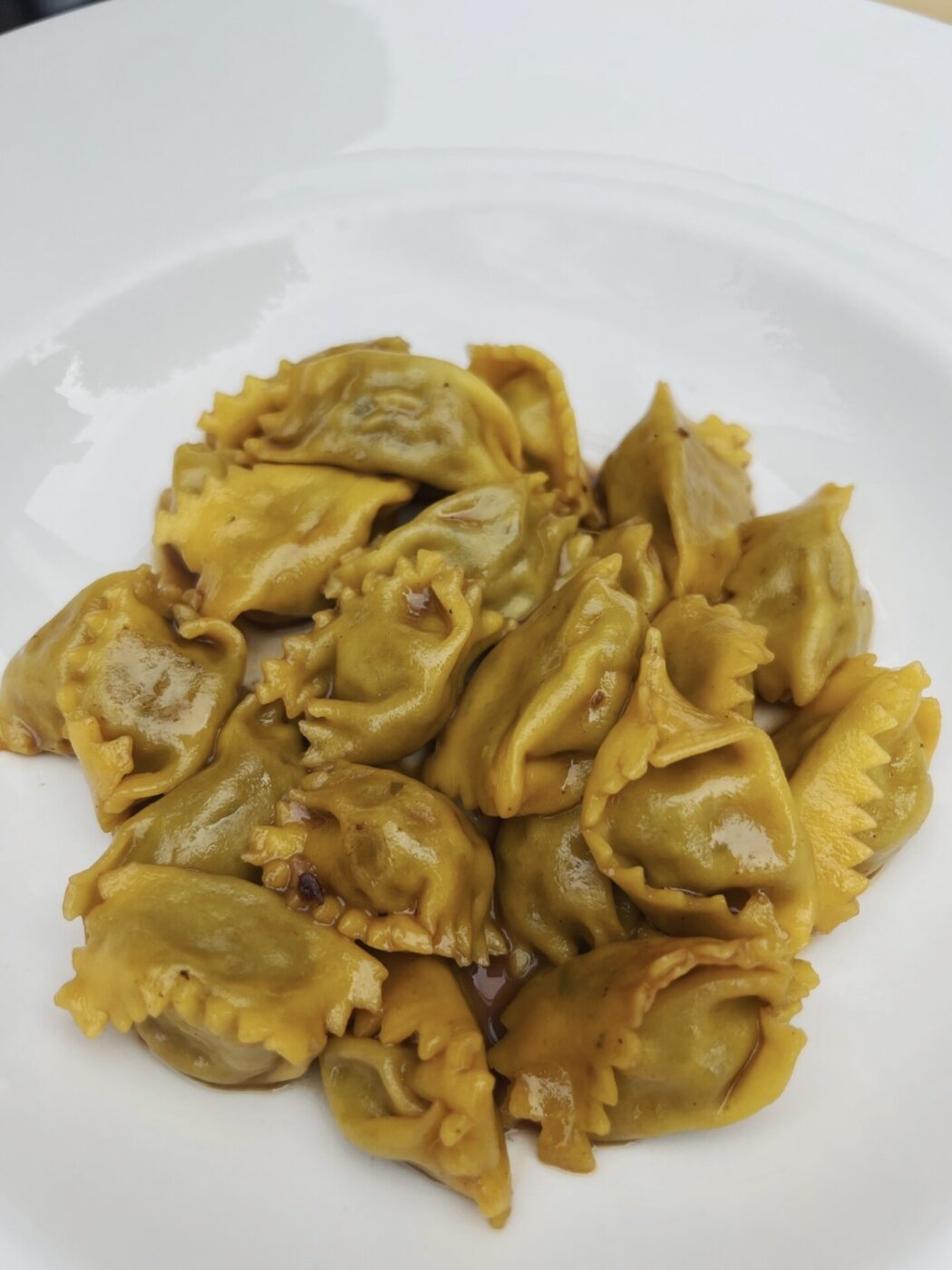 a bowl of agnolotti del plin in arrosto sauce