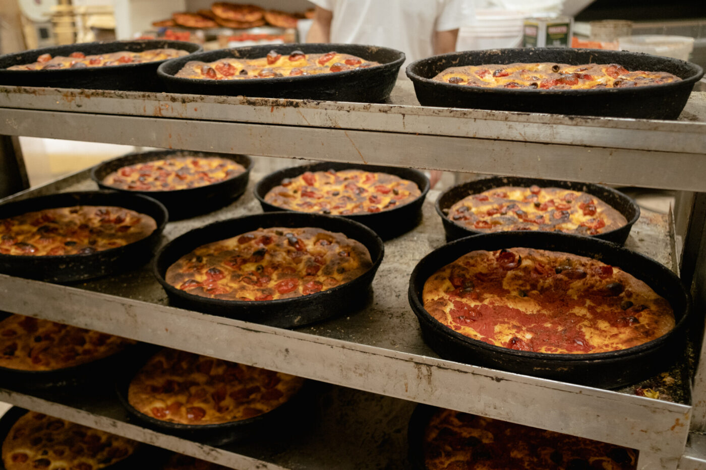 shelves of fresh baked Focaccia Barese topped with toamtoes