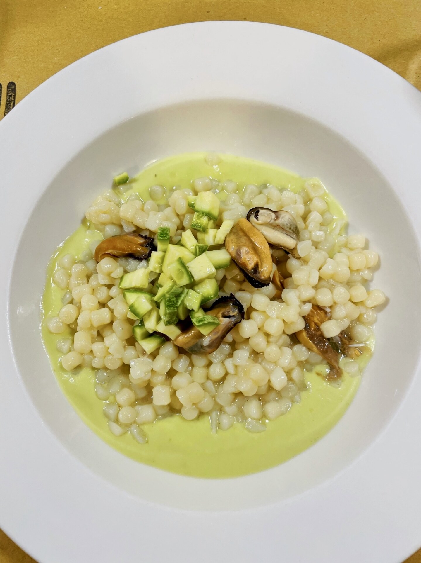 a bowl of fregola with mussels and zucchini