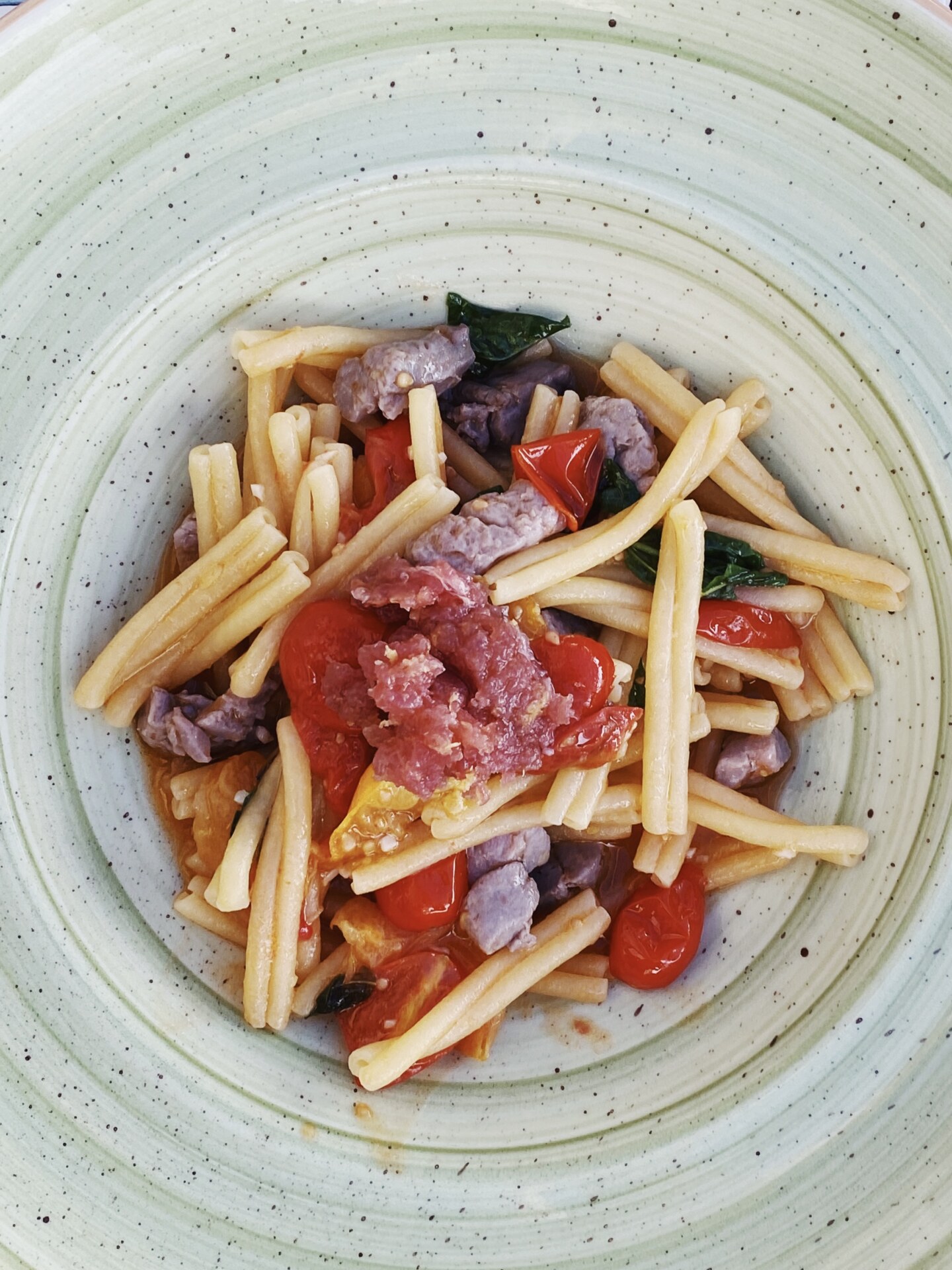a bowl of strozzapreti with sausage and tomatoes