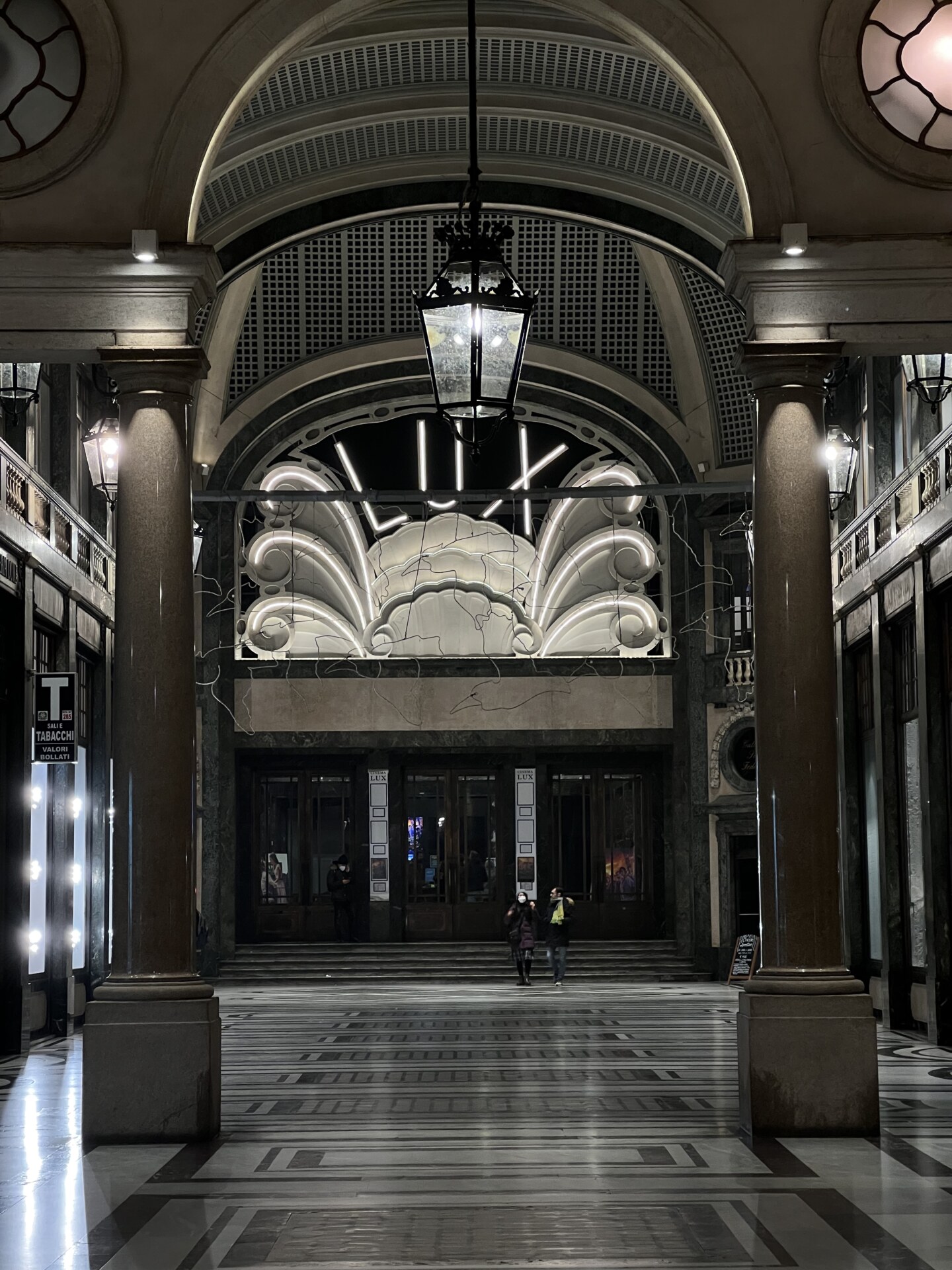 a white neon sign that says LUX in a galleria in Torino