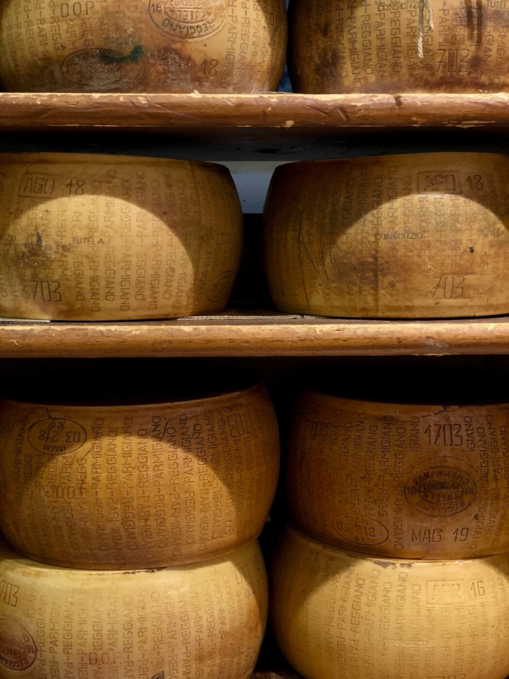 wheels of golden parmesan on wooden shelves aging