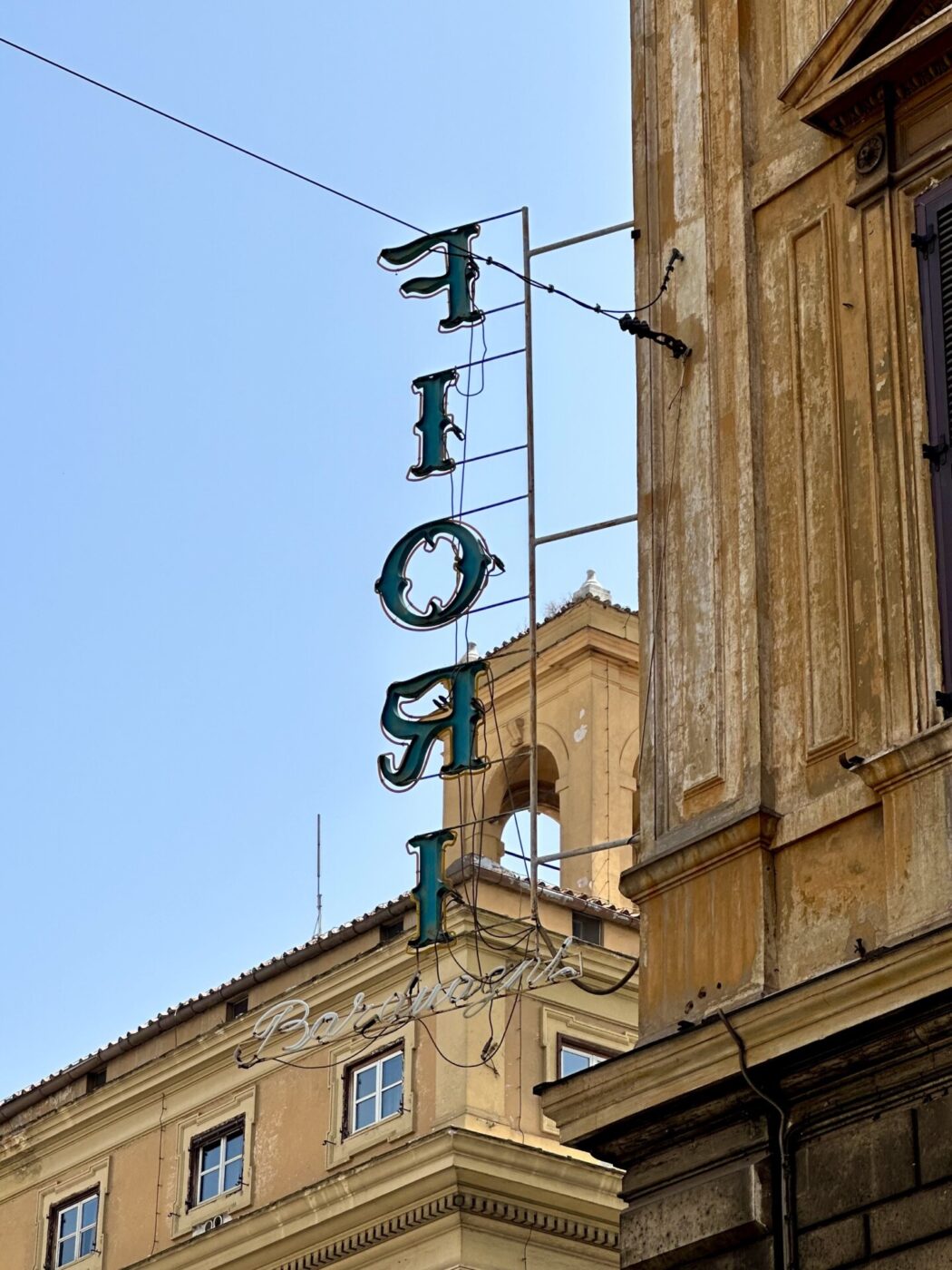 a vertical lettered sign for Fiori taken from behind hanging off of a building