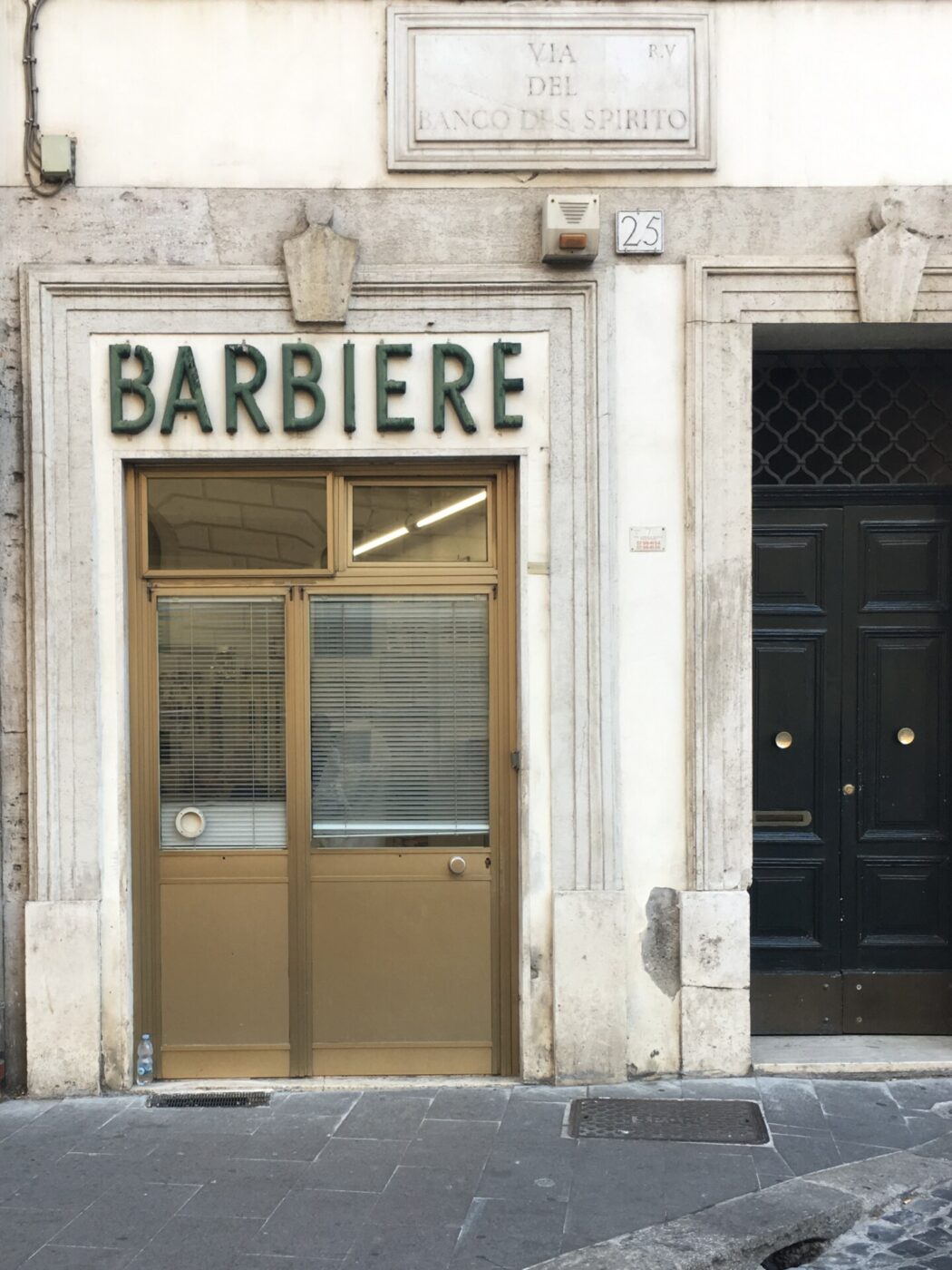 a sign for a barbiere over a light wooden door