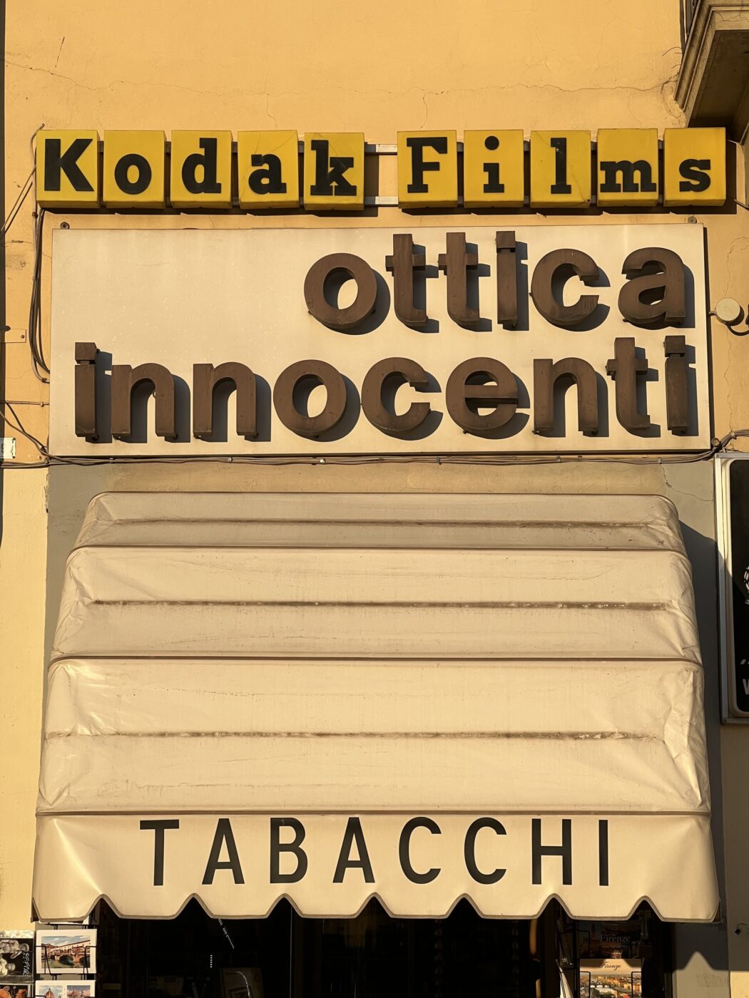 [Image Title] - The image shows a store facade featuring a Kodak Films sign on top, with ottica innocenti in large brown letters. Below is a cream-colored awning with TABACCHI printed on it. (Note: Please replace [Image Title] with the actual title of the image if provided.).